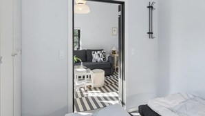 A modern room with a bed, a sofa, a small table, and a chair. There is a door leading to another room.