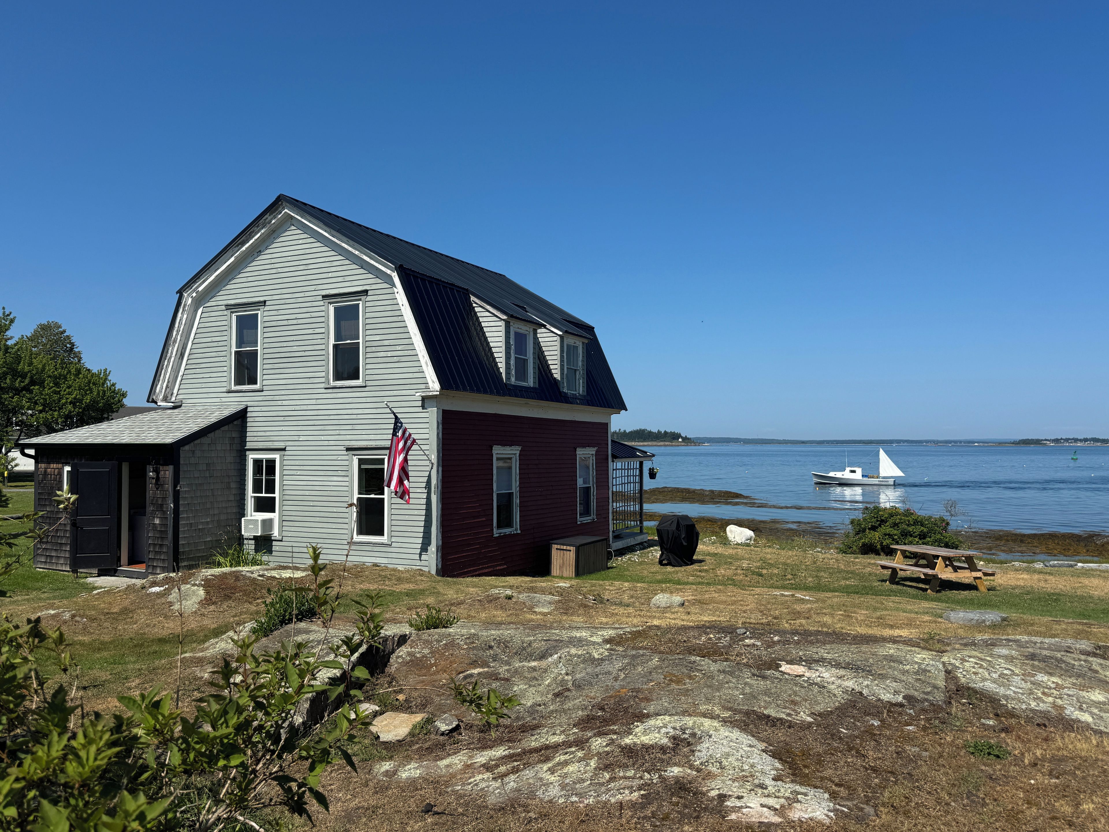 A two-story house with a dock and a boat in the background.