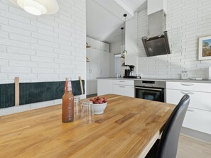 Eine moderne Küche mit weißen Backsteinwänden, einem Holzespeisetisch und einem eingebauten Backofen.