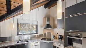 Eine moderne Küche mit Granit-Arbeitsplatten, Edelstahlgeräten und einem Fenster mit Blick auf Bäume.
