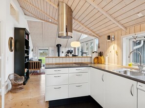 Een moderne keuken met witte kasten, een roestvrijstalen spoelbak en een houten plafond.