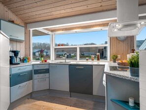 A modern kitchen with a large window, wooden ceiling, and a built-in stove. - "Lien" - 100m from the sea by Interhome (Juelsminde)