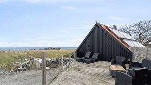 Eine moderne Außenterrasse mit Sitzgelegenheiten und Meerblick.