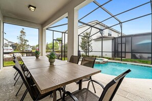 Eine überdachte Terrasse mit Pool, Gartenmöbeln und Blick auf die Nachbarhäuser.