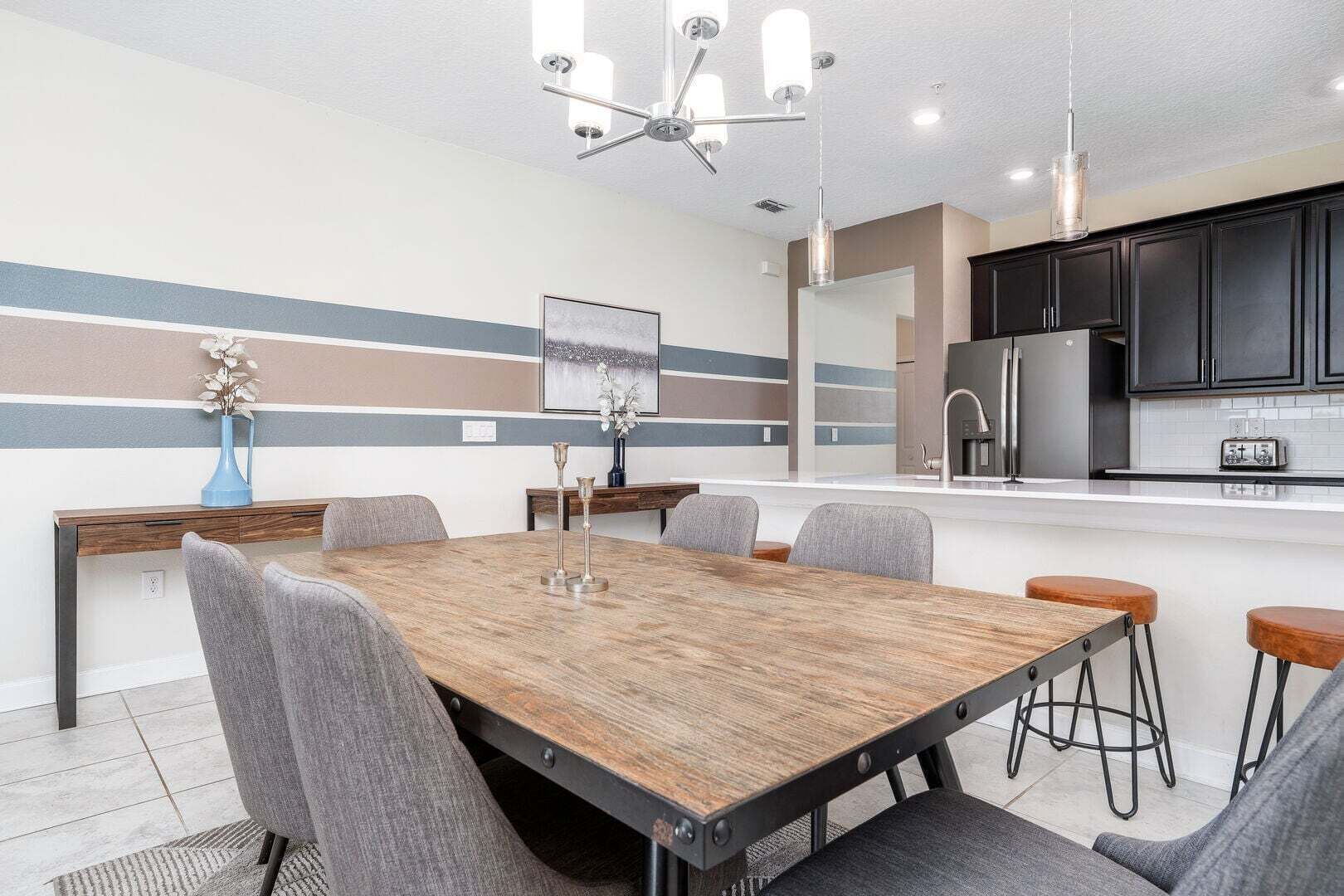 Una cocina moderna con una isla central, una zona de comedor con mesa y sillas de madera, y una encimera con un tostador.