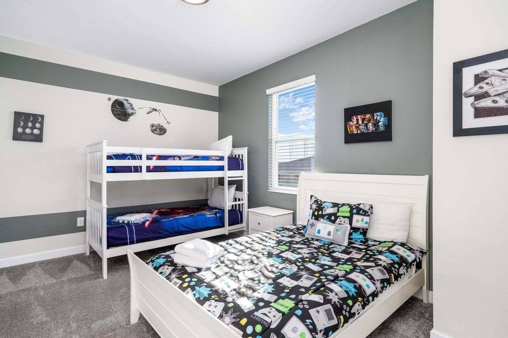 A bedroom with bunk beds, a single bed, a window, and wall decorations.