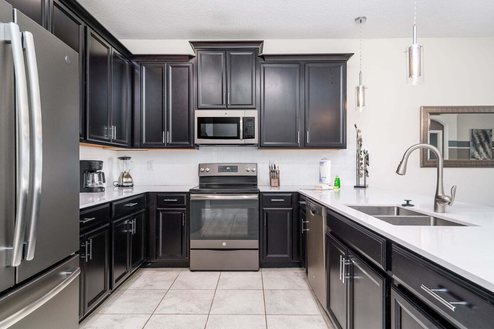 A modern kitchen with dark cabinetry, stainless steel appliances, and a white countertop.