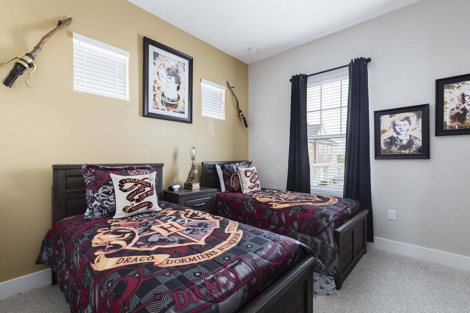 A bedroom with two beds, a window with curtains, and framed artwork on the walls.