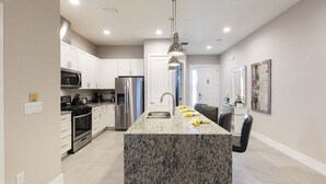 Eine moderne Küche mit Granit Arbeitsplatten, Edelstahlgeräten und Pendelleuchten.