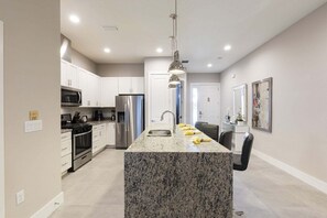 A modern kitchen with granite countertops, stainless steel appliances, and pendant lighting. - Amazing Family Villa 5min-disney BBQ 128 (Kissimmee)