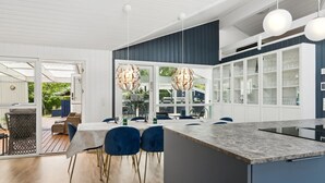 Een moderne keuken met een groot eiland, donkere kastjes en hanglampen.