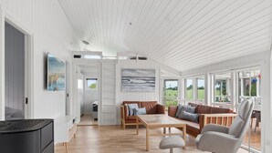 Een ruime woonkamer met houten vloer, een zithoek, een salontafel en een televisie.