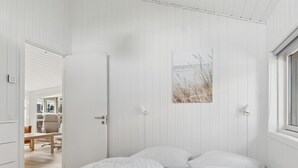Een slaapkamer met een bed, een deur, een raam en een schilderij aan de muur.