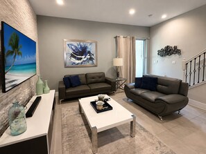 A modern living room with a sofa, coffee table, and artwork on the wall. - Close 5min to Disney Fantastic Townhome BBQ 152 (Kissimmee)
