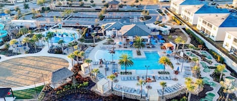 Un resort con piscina central, zonas de descanso y aparcamiento.