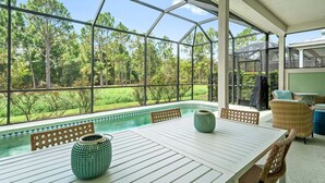 Un espace extérieur abrité comprenant une piscine, des sièges et une vue sur les arbres environnants.