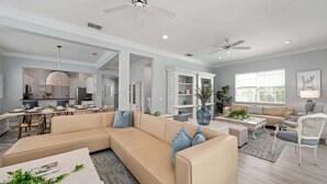 Un salon moderne avec un canapé d’angle, un coin repas et une cuisine en arrière-plan.