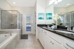 Un baño moderno con cabina de ducha, bañera, tocador doble y un espejo grande.