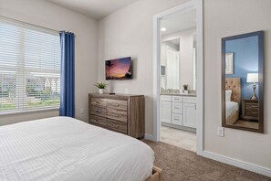 A bedroom with a bed, a dresser, a painting, a mirror, and a view through a door. - Comfortable Home w 3 En-suites! (Kissimmee)