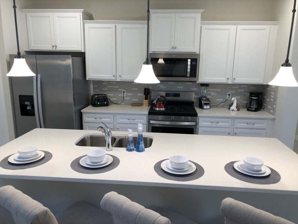 A modern kitchen with white cabinets, stainless steel appliances, and a central island with seating.