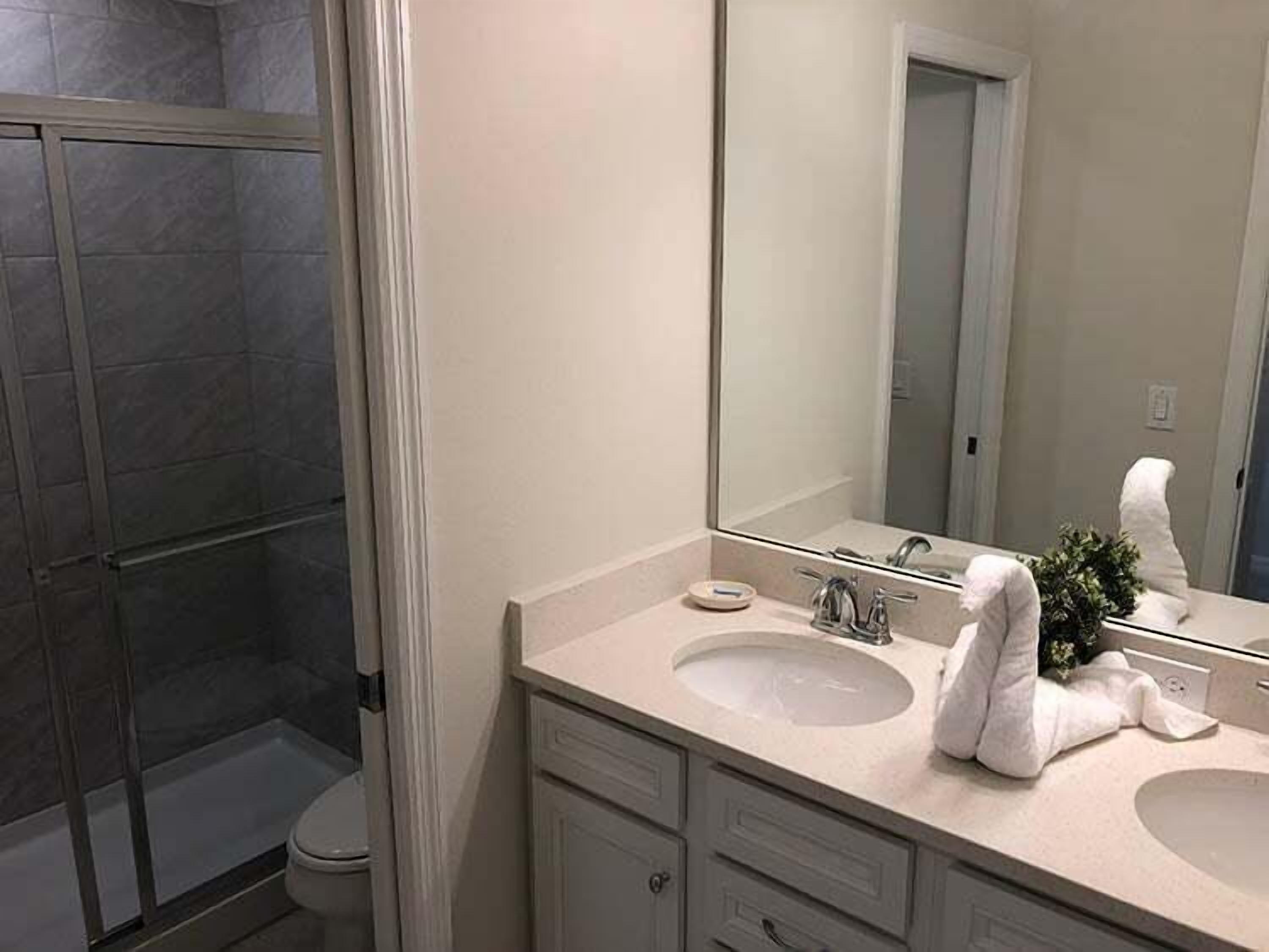 A bathroom with a shower, two sinks, a large mirror, and a towel.