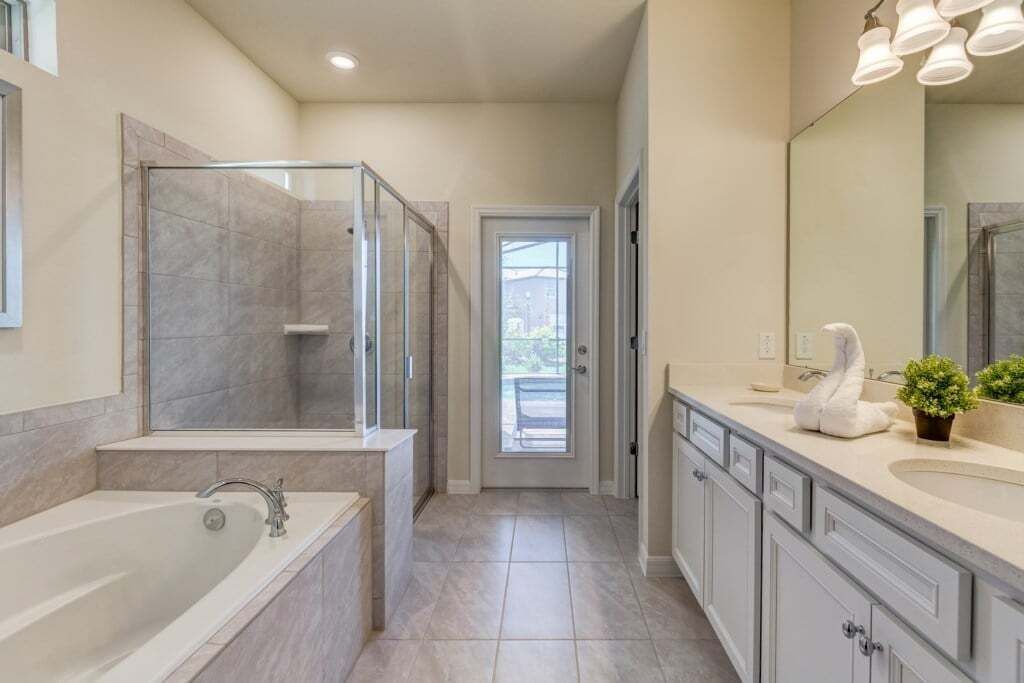 A modern bathroom with a glass-enclosed shower, a large bathtub, and a vanity with a mirror.