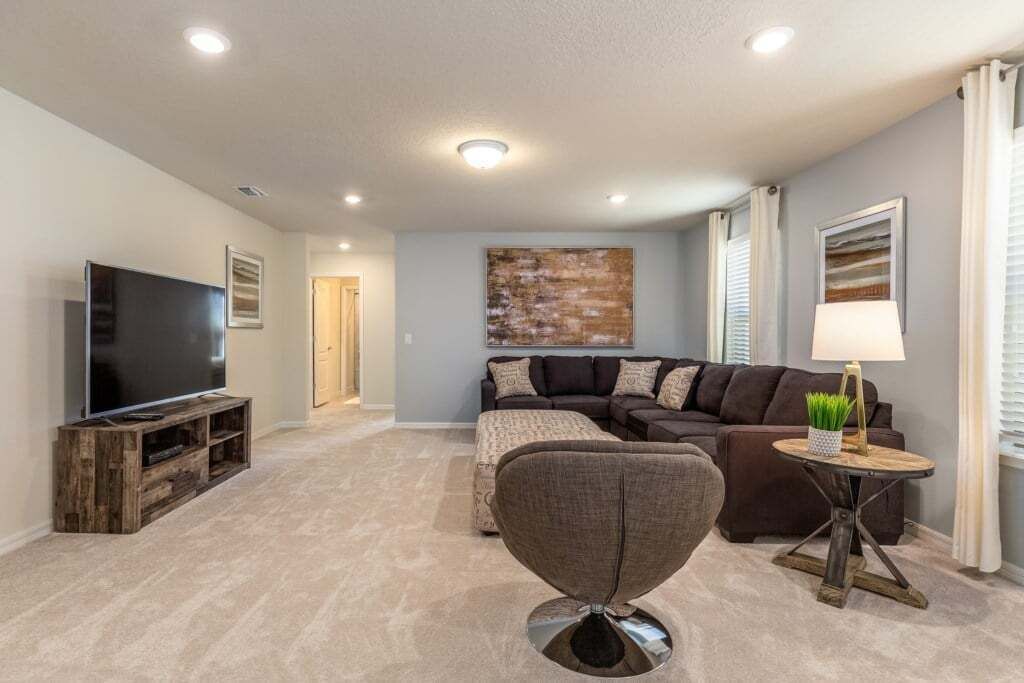 A living room with a flat-screen TV, a sectional sofa, a coffee table, and a painting on the wall.