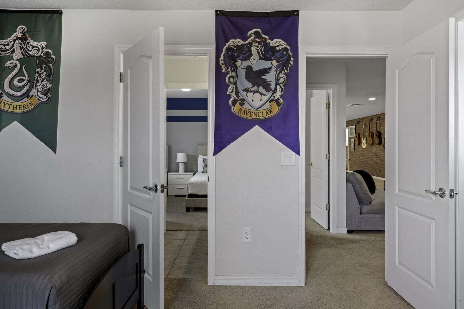 Une chambre avec un lit, une table de chevet, une lampe et une armoire. Il y a deux portes ornées de bannières.