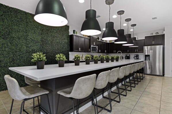 A modern kitchen with a central island, bar stools, pendant lighting, and a green wall. - Comfortable Vacation Home - Great Resort Pool/spa Sleeps 20 Ww101 (Kissimmee)