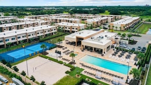 Ein Hotel mit mehreren Gebäuden, einem Schwimmbad und einem Tennisplatz.
