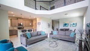 A spacious living area with two sofas, a coffee table, and a kitchen in the background. - Champions Gate Gem Pool, Spa, Near Parks (Davenport)
