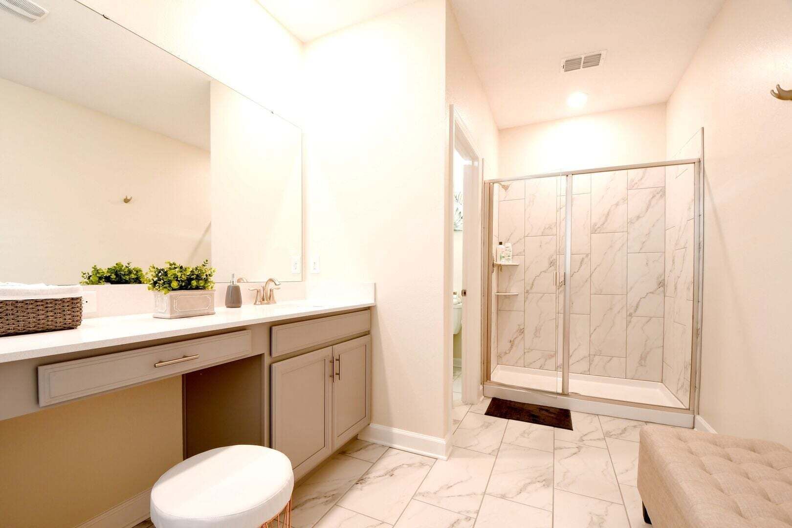 A bathroom with a vanity, sink, mirror, toilet, and a glass-enclosed shower.