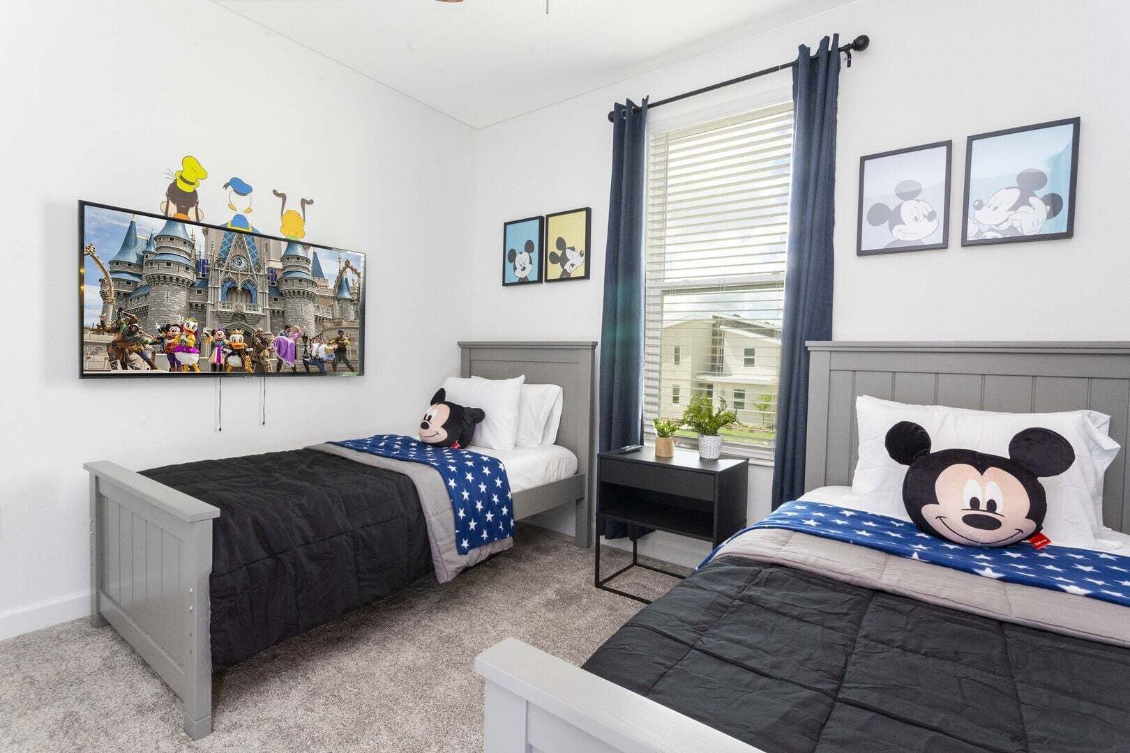 A hotel room with two beds, a large Disney-themed painting, and Mickey Mouse pillows.