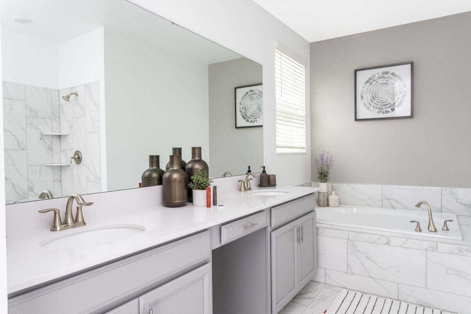 Un baño moderno con un espejo grande, dos lavabos, una bañera y baldosas de mármol.