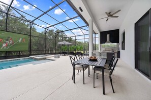 Eine moderne Außenpatio mit Pool, Essbereich und Küche.