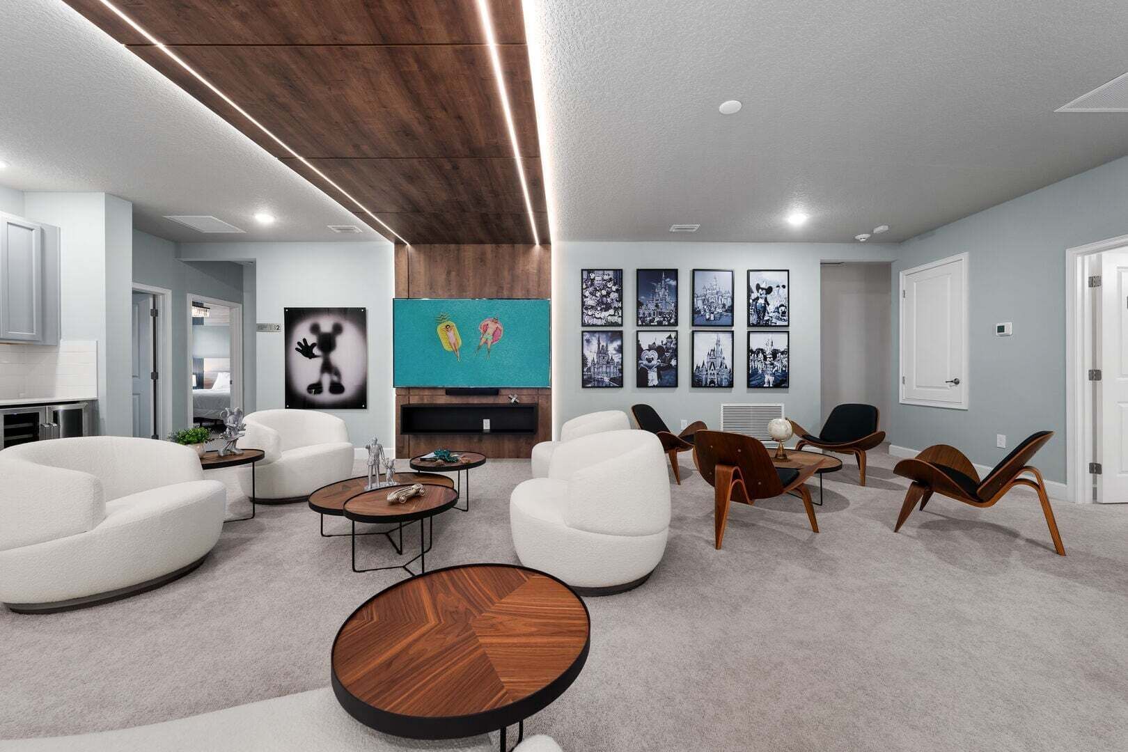 Een moderne woonkamer met witte banken, een houten salontafel en een televisie bevestigd aan een houten wand.