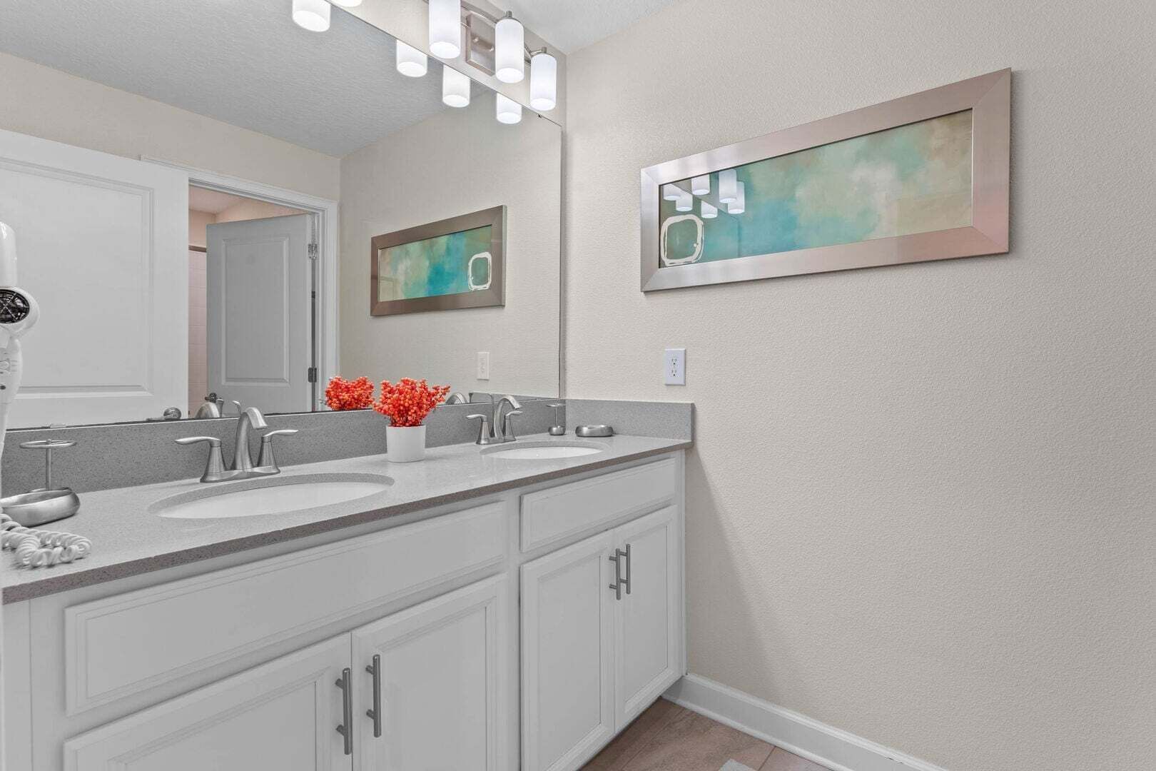 A bathroom with two sinks, a large mirror, and a wall-mounted light fixture.