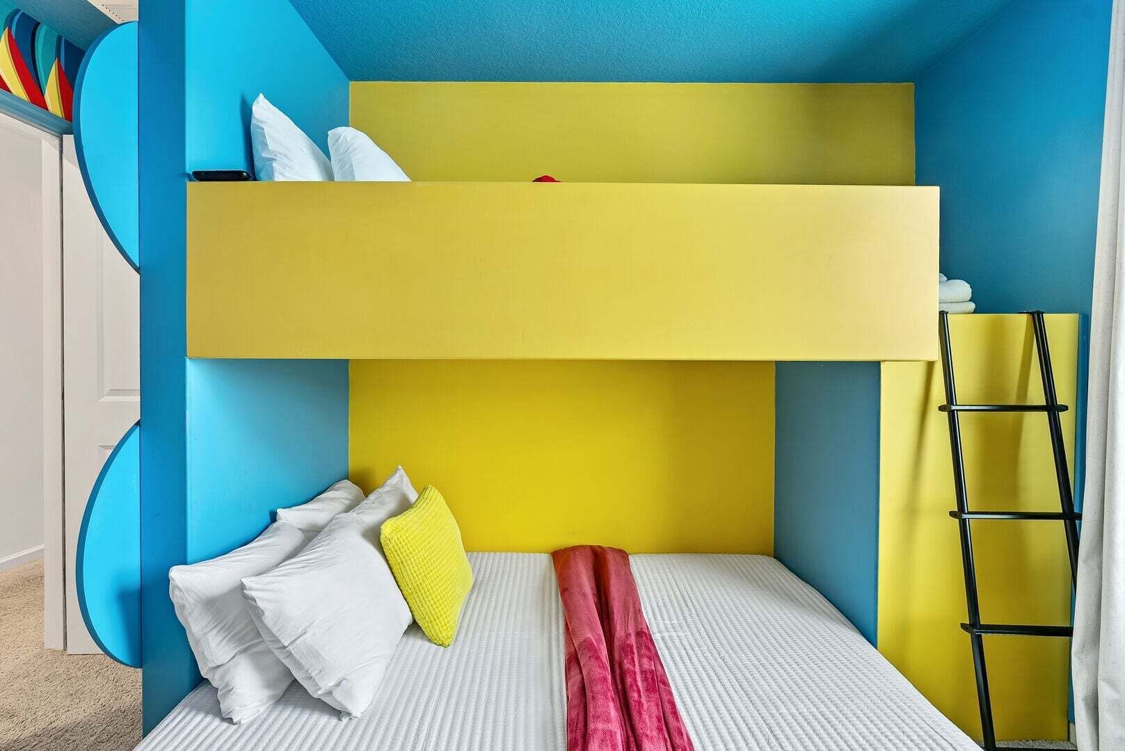 Un lit superposé avec une tête de lit jaune, du linge de lit blanc et une serviette rouge.