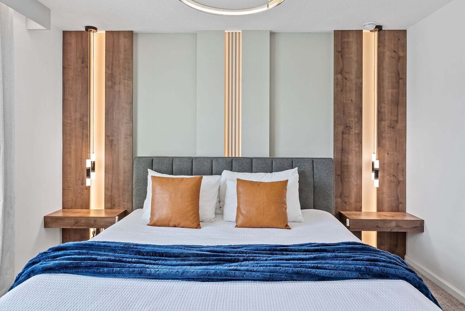 A modern bedroom with a large bed, two bedside tables, and a unique wall design.