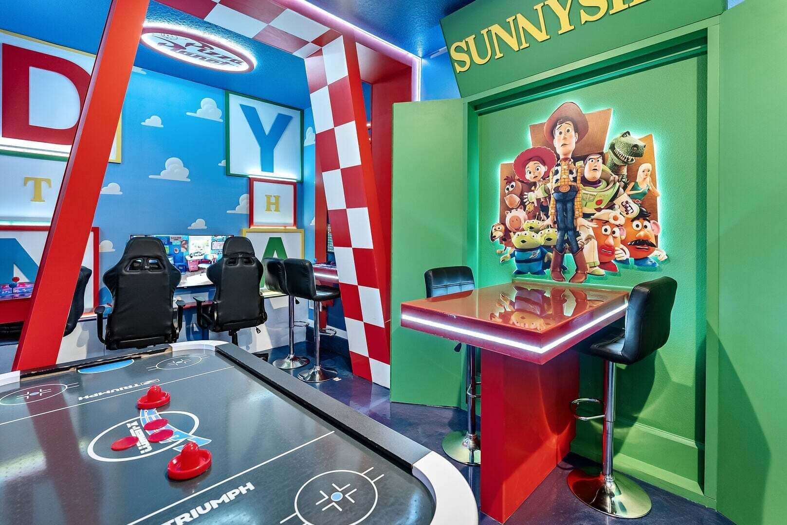 Une pièce équipée d’un baby-foot, de fauteuils de jeu et d’un mur décoré de personnages de dessins animés.
