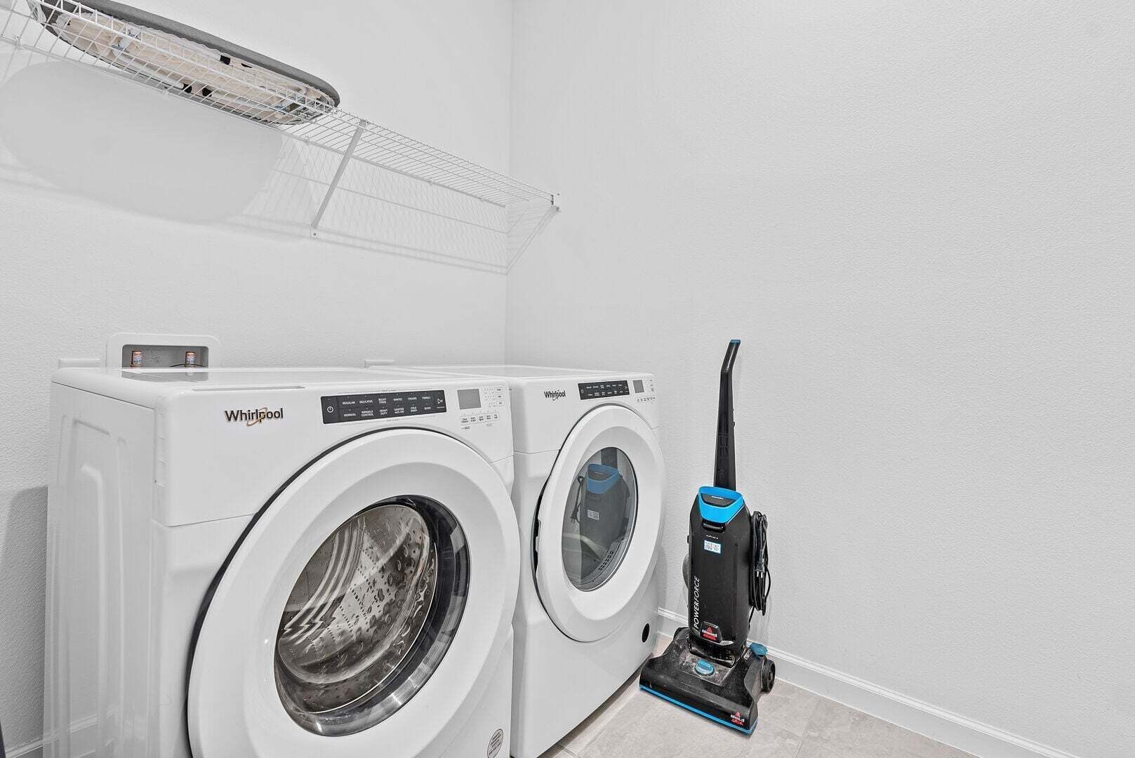 A laundry area with two Whirlpool washers and a PowerStrap vacuum cleaner.