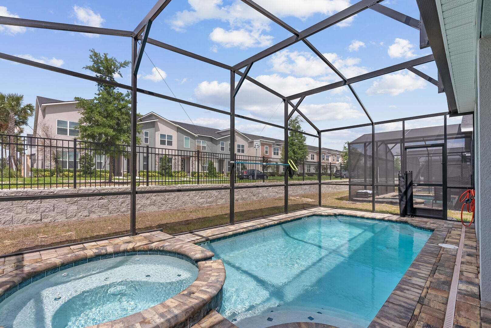 Une piscine avec un jacuzzi, entourée d’une zone couverte d’où l’on peut admirer les immeubles résidentiels.