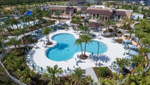 Un resort con piscina central, rodeado de palmeras y sillas de descanso.
