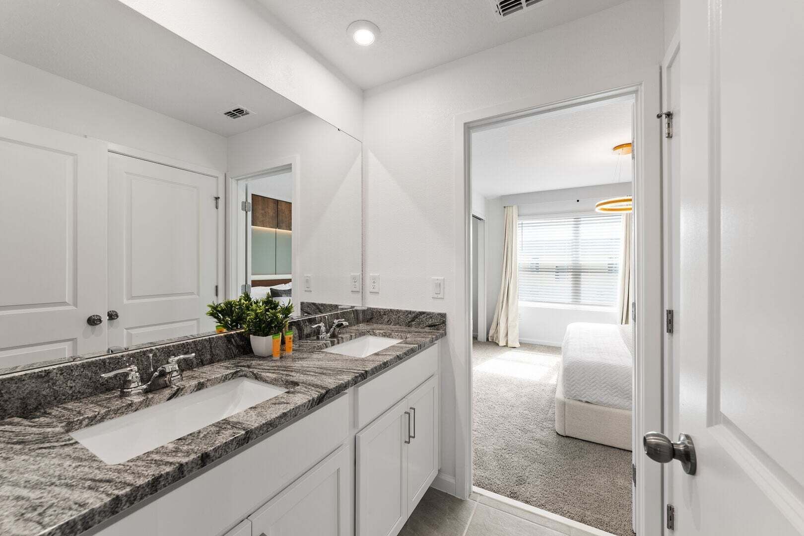A modern bathroom with a double sink, granite countertop, and a mirror.