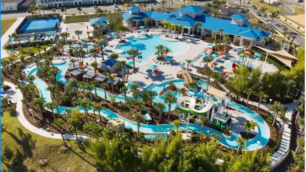 Un complexe hôtelier doté de plusieurs piscines, de palmiers et d’un grand bâtiment surmonté d’un toit bleu.