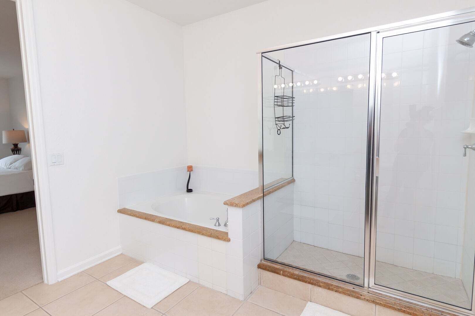 A modern bathroom with a glass-enclosed shower, a standalone bathtub, and a white tiled floor.