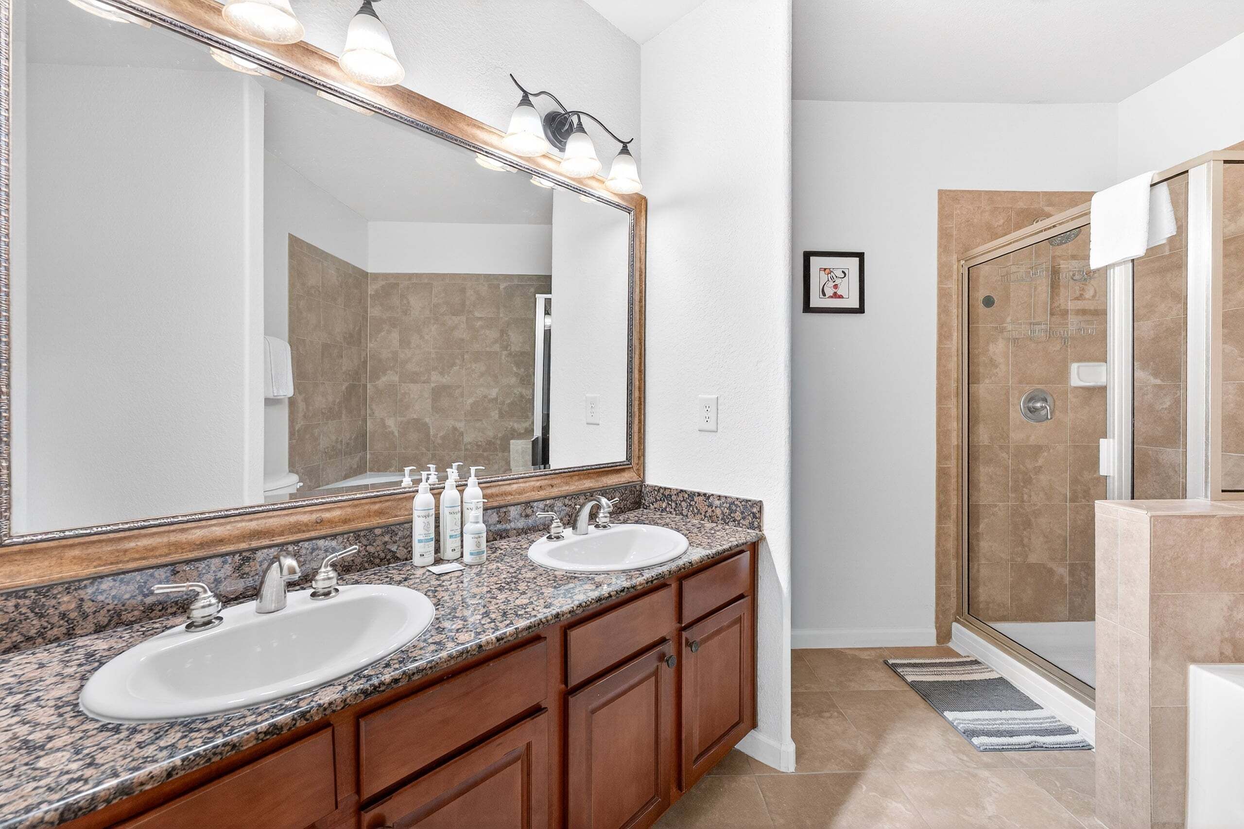 Une salle de bain avec deux lavabos, un grand miroir et un espace douche.
