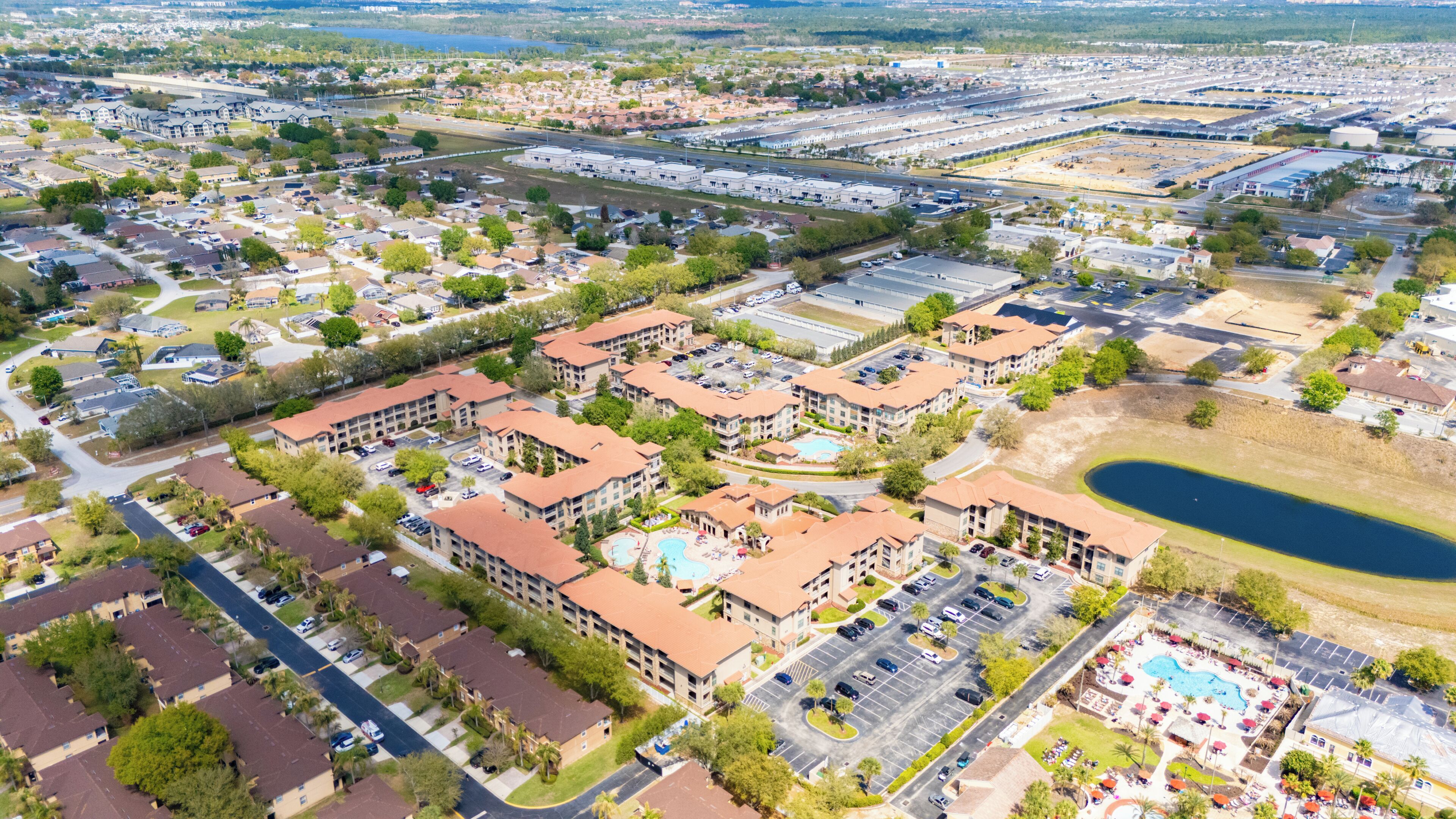 A residential area with apartment buildings, a swimming pool, and a large parking lot.