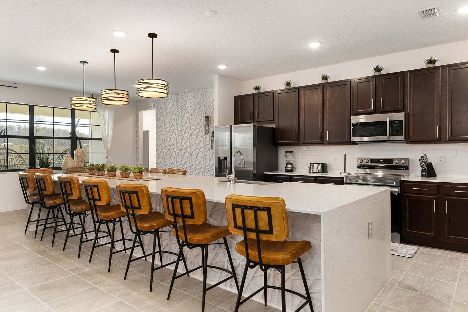 A modern kitchen with dark wood cabinets, stainless steel appliances, and a central island with bar stools.