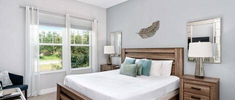 A bedroom with a bed, bedside tables, a ceiling fan, a window with curtains, and a wall-mounted mirror.